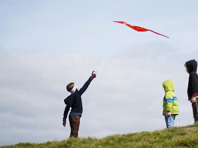 3 kids flying a kite outside