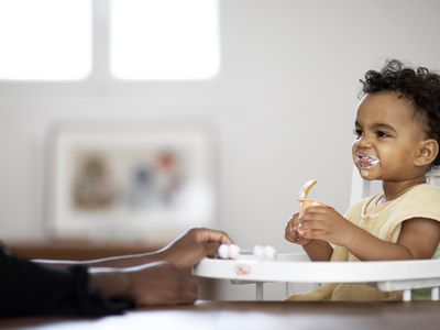 Baby feeding himself yoghurt