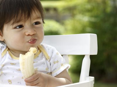 Close shot of baby eating a banana