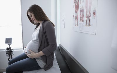 Smiling pregnant female patient waiting in clinic examination room