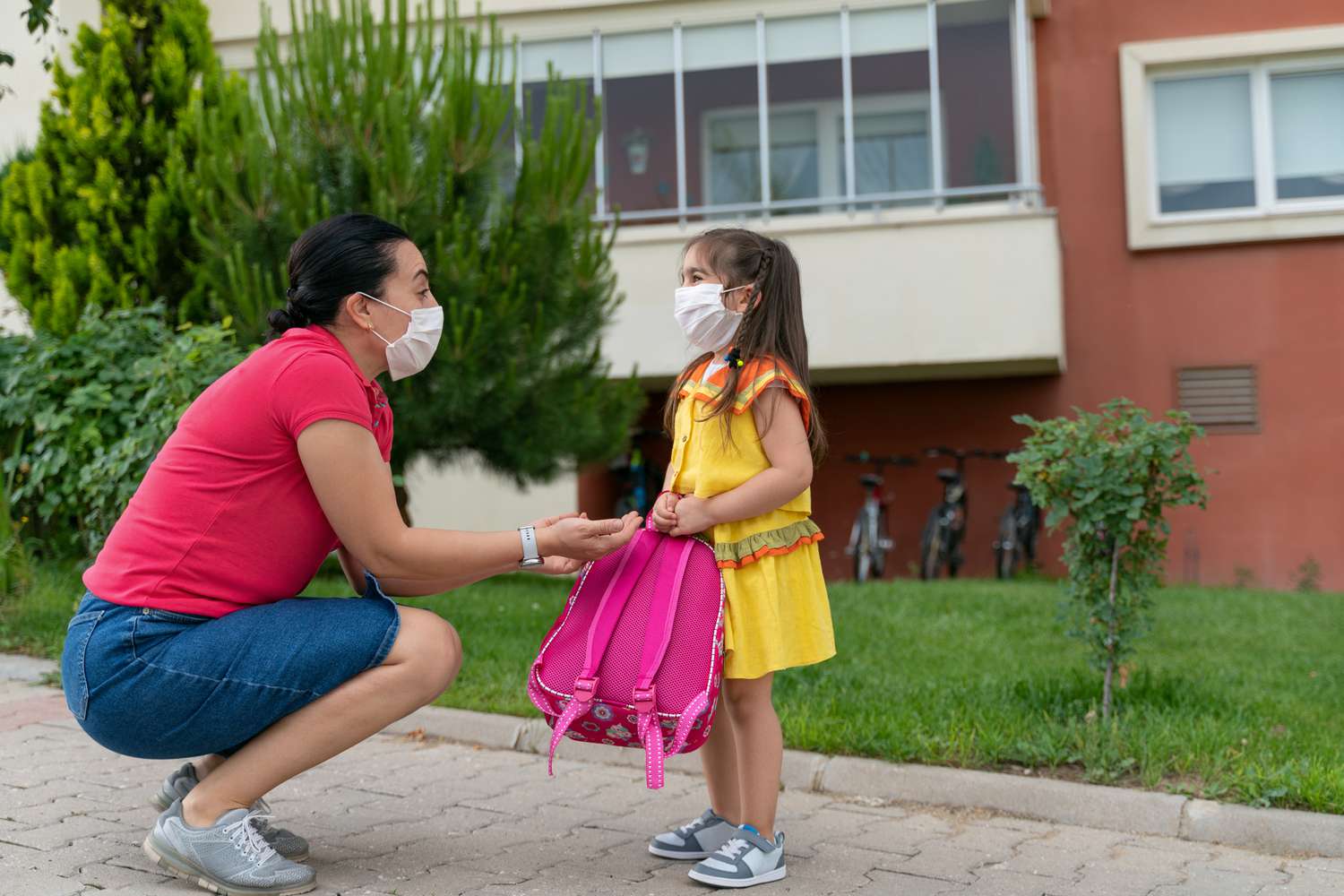 Woman and child wearing masks outside of a school