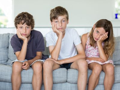 Brothers and sister on sofa looking annoyed