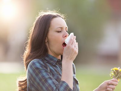 Woman sneezing while holding tissue