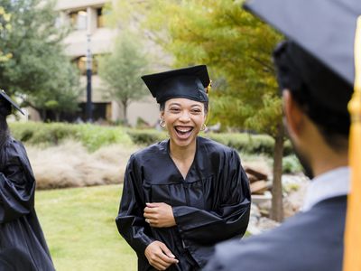 Young adult friends smile and laugh after the graduation ceremony