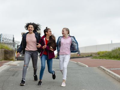 Three cheerful teenage girls arm in arm