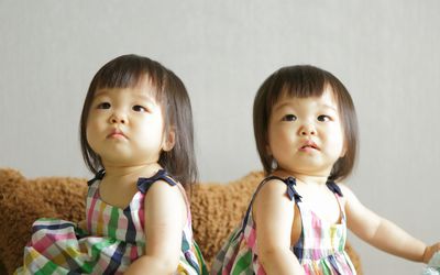 双胞胎女孩穿着一模一样的衣服坐在一起咳嗽