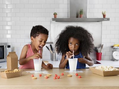 Brother and sister drinking milk in the kitchen