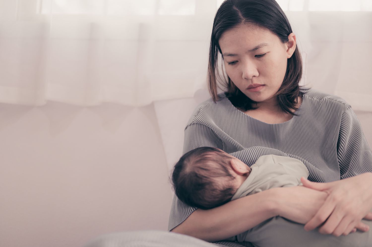 女人严肃地坐在那里，怀里抱着孩子