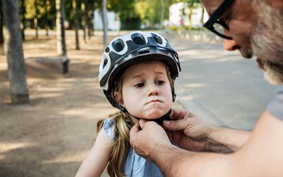 Grandpa putting helmet on granddaughter