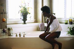 年轻女子坐在浴缸边。