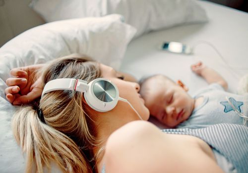 新妈妈一边听音乐，一边陪孩子睡觉