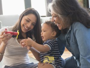 Mother and grandmother playing on floor with baby boy