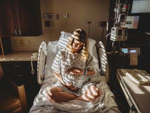 公关egnant woman sitting on hospital bed holding her belly