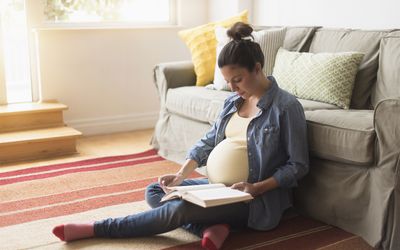 美国新泽西州，孕妇坐在地板上看书