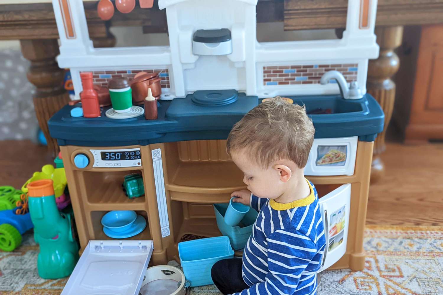 Toddler playing with Step2 Fun with Friends Kitchen displayed on carpet