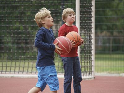 Boys holding basketballs while looking up at court