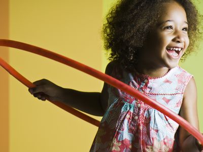 A smiling little girl playing with a hula hoop