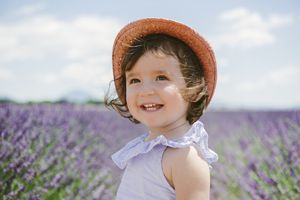 戴着帽子的小女孩在一片紫色的花中