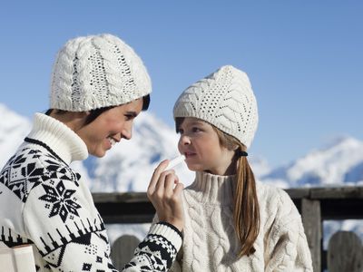 Mother applying lip balm to her daughter