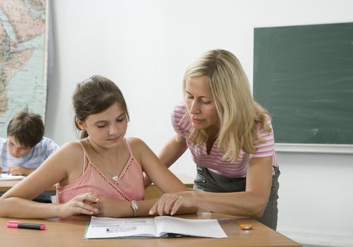 A teacher helping a student in a classroom.