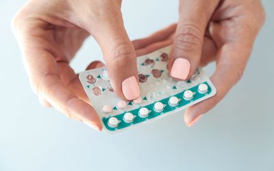 Women's hands hold birth control pills