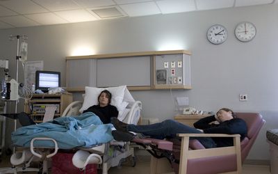 孕妇在医院的床上，男人睡在躺椅上