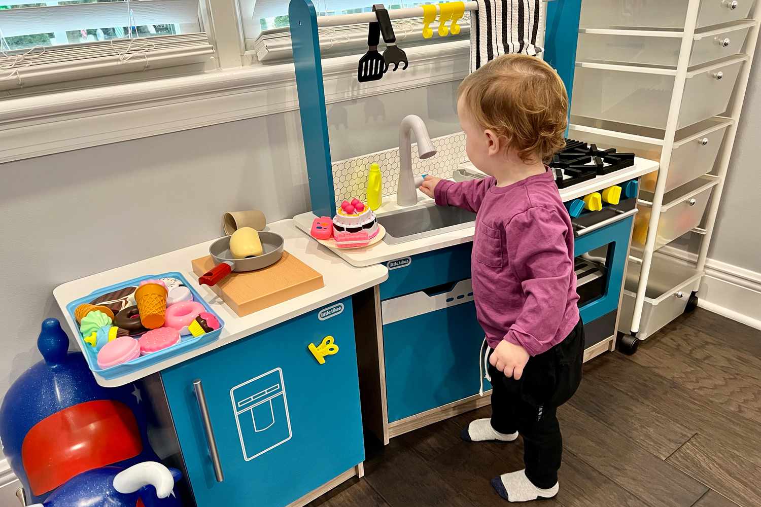 Toddler playing with Little Tikes Real Wood Kitchen with Island displayed on floor