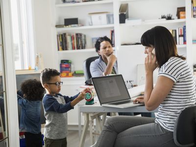 Parents working in home office with children playing