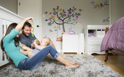 中间的成年夫妇玩婴儿玩具和婴儿的女儿在膝上