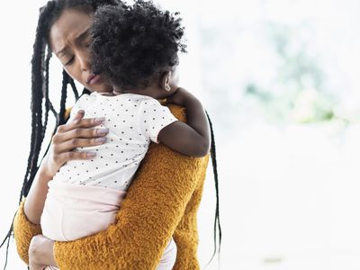 Woman holding and comforting baby daughter