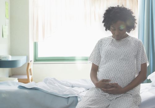 怀孕的非裔美国妇女在医院抱着自己的胃
