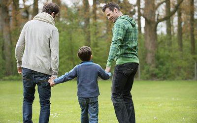 一个男孩和两个男人在公园里散步的后视图