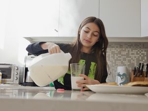 一个小女孩正在厨房里倒一杯牛奶