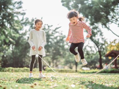 Young family jumping rope joyfully on the lawn