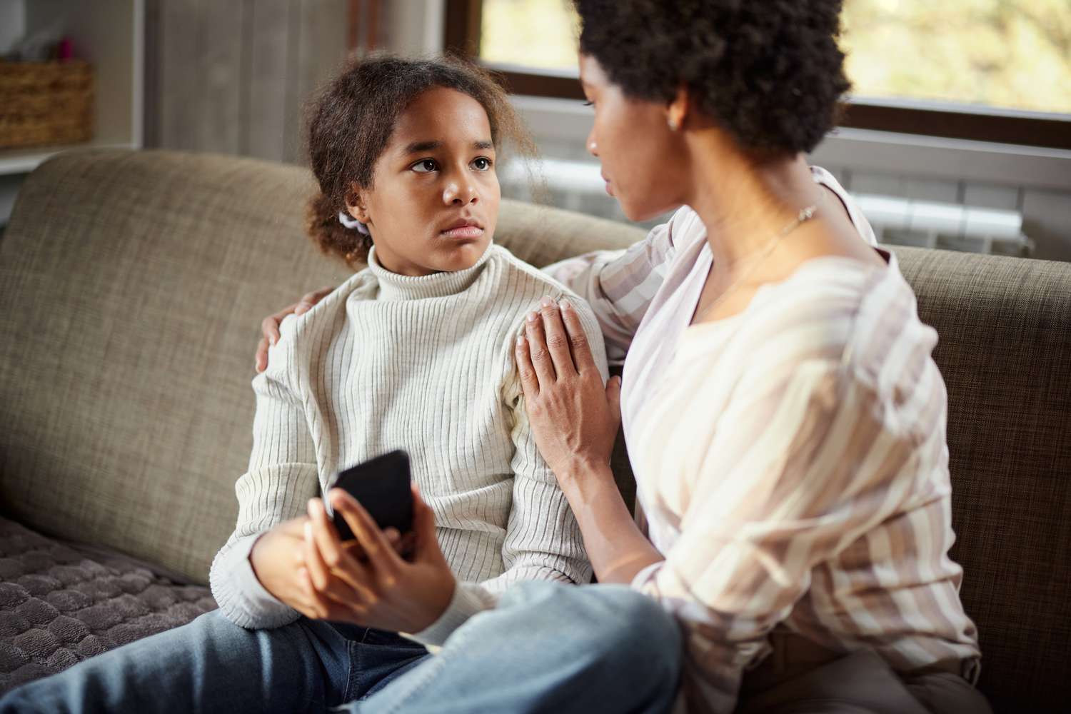 Sad girl talking to her mother at home