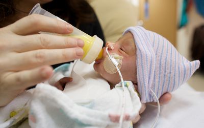 Premature baby drinking breastmilk from a bottle