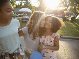 Affectionate mother kissing daughters cheek at party