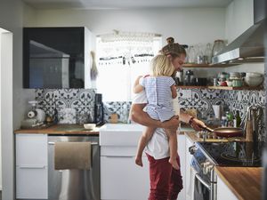 一个男人在厨房里抱着一个小孩做饭