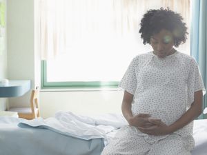 身着病号服的孕妇坐在靠窗的病床上