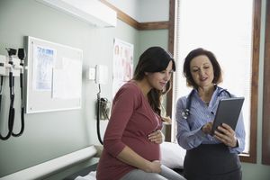 Doctor and pregnant woman looking at digital tablet