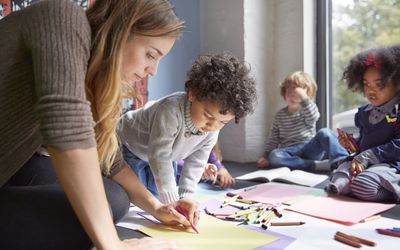 Teacher drawing with students on floor at preschool