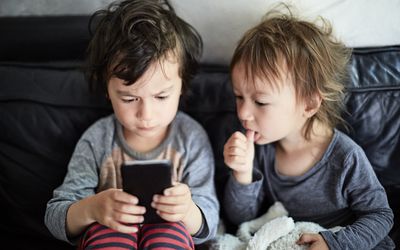 two young children looking at a smart phone