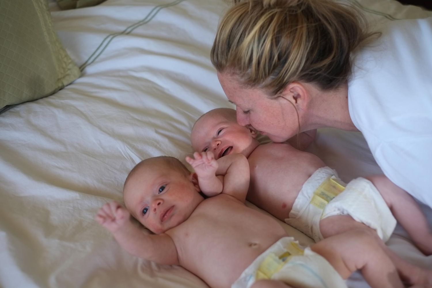 Mother kissing twin babies.