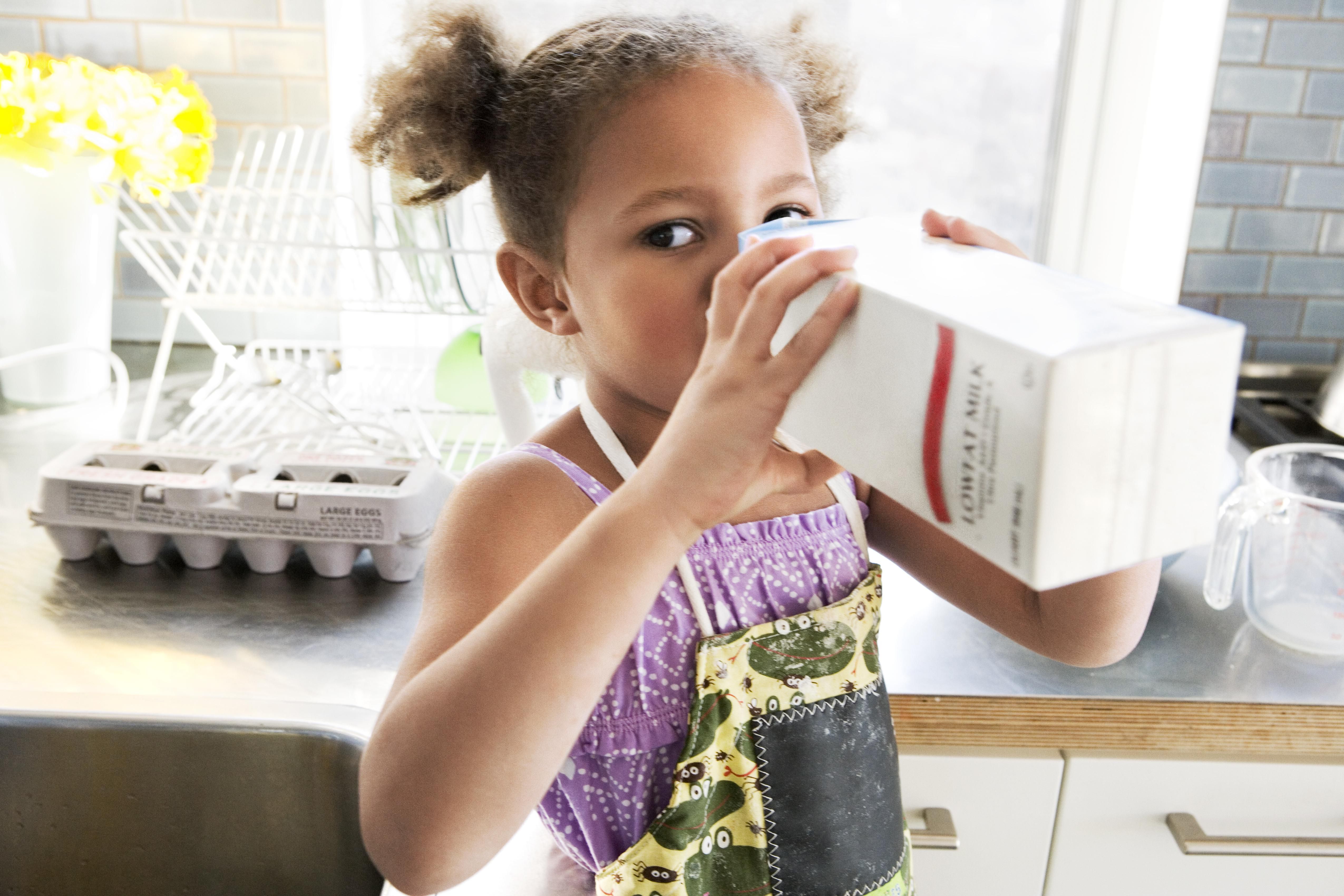 小孩子从纸盒里喝牛奶