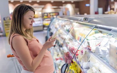 Pregnant person at a deli counter holding cheese