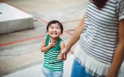 Smiling toddler holding hands with mom in park