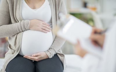 Pregnant woman holding stomach in doctor's office