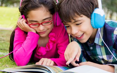 孩子们戴着耳机听有声书和阅读
