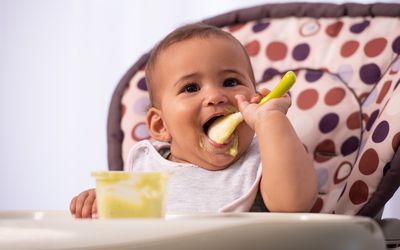 Baby messily eating food by himself