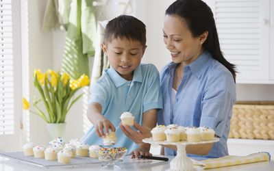 Asian mother and son decorating cupcakes